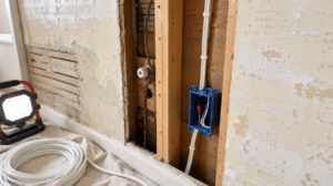 Open plaster wall showing new cable and old knob and tube wiring while rewiring a house in Northeast Ohio